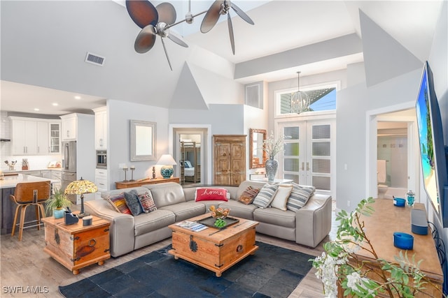 living area with french doors, visible vents, a high ceiling, ceiling fan, and wood finished floors