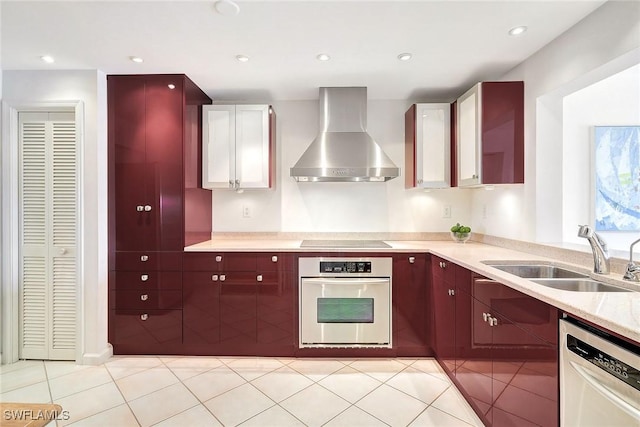 kitchen featuring light tile patterned floors, wall chimney range hood, sink, and appliances with stainless steel finishes