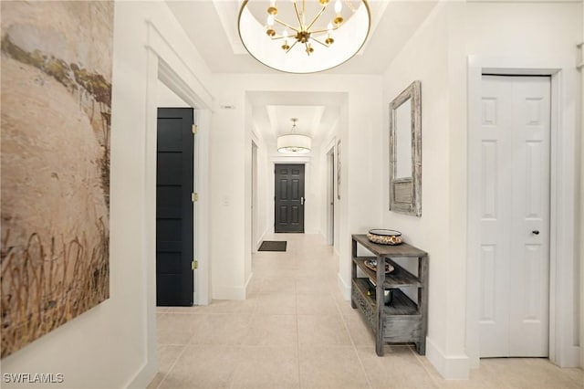 hallway with light tile patterned flooring and an inviting chandelier