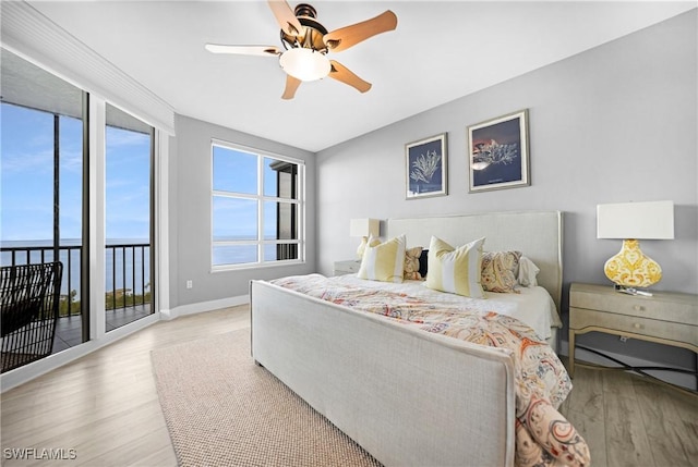 bedroom featuring ceiling fan, access to exterior, light wood-type flooring, and a water view