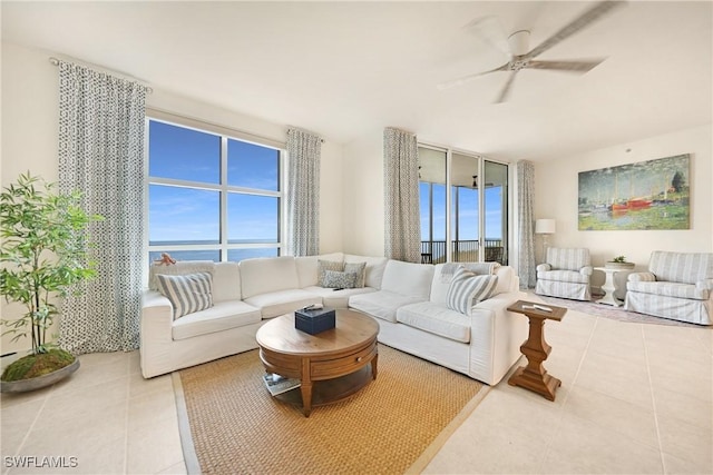 tiled living room with ceiling fan and a water view