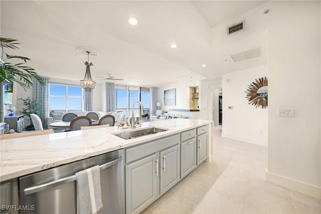 kitchen featuring light stone counters, stainless steel dishwasher, ceiling fan, sink, and hanging light fixtures