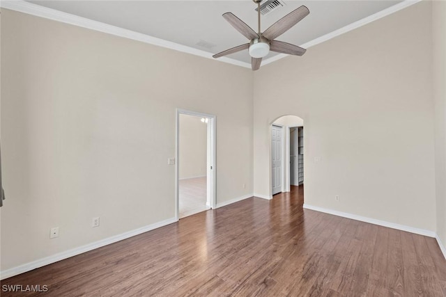 spare room featuring ceiling fan, a towering ceiling, dark wood-type flooring, and ornamental molding