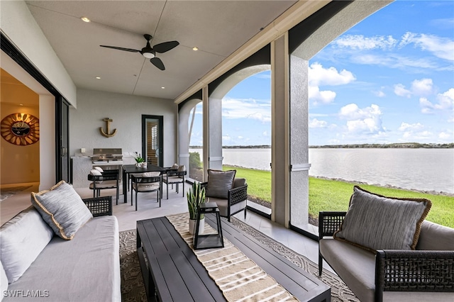 sunroom / solarium featuring ceiling fan and a water view