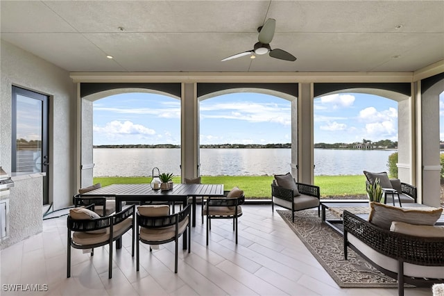 sunroom / solarium with ceiling fan and a water view