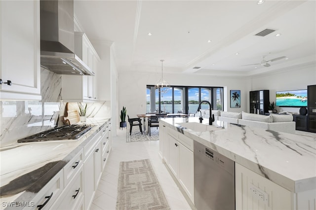 kitchen featuring light stone countertops, sink, wall chimney range hood, white cabinets, and appliances with stainless steel finishes