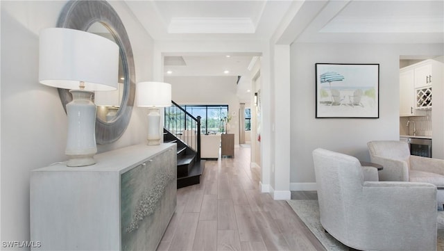 hallway featuring light wood-type flooring, ornamental molding, and sink