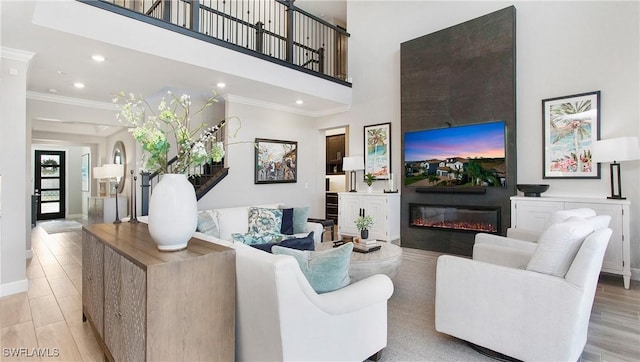 living room featuring crown molding, light wood-type flooring, and a fireplace