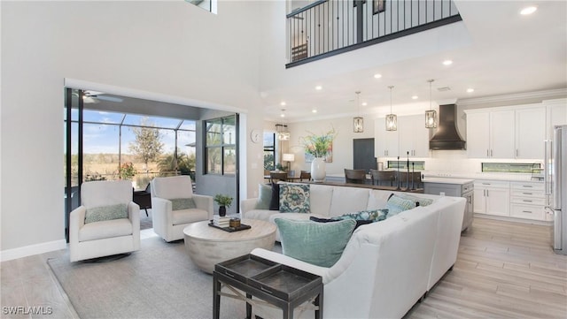 living room featuring a high ceiling, light hardwood / wood-style floors, ceiling fan, and ornamental molding