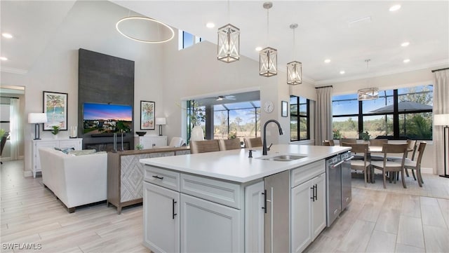 kitchen with ceiling fan, sink, hanging light fixtures, a towering ceiling, and a kitchen island with sink