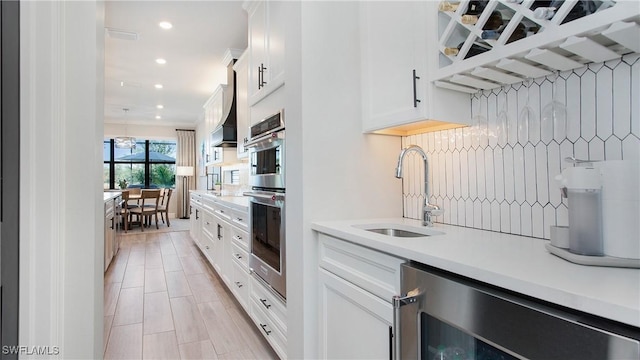 kitchen featuring white cabinetry, sink, and beverage cooler