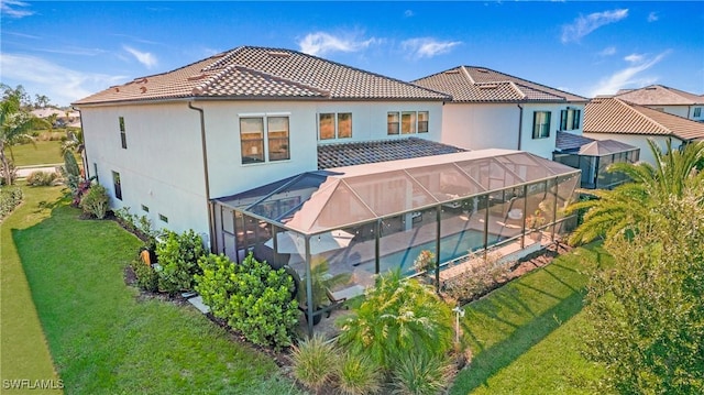 rear view of property with a yard and a lanai