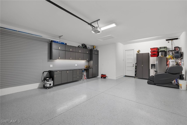 garage with stainless steel fridge and a garage door opener