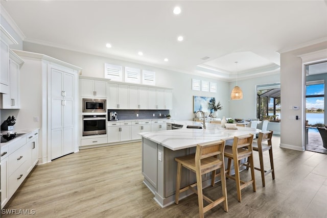 kitchen featuring a breakfast bar, a sink, appliances with stainless steel finishes, crown molding, and decorative backsplash