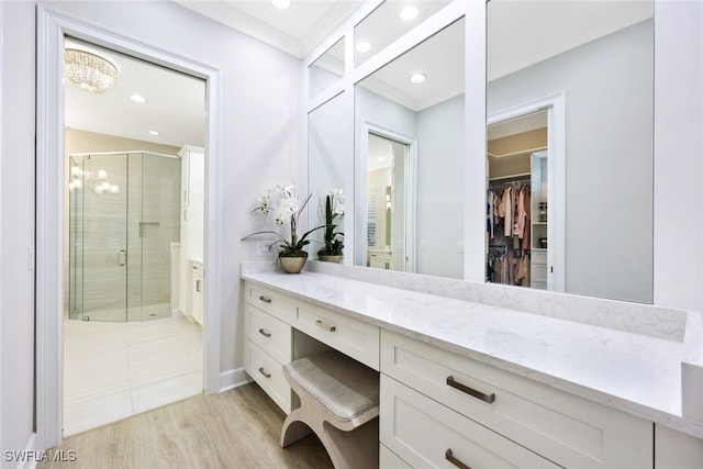 full bath featuring a stall shower, wood finished floors, recessed lighting, vanity, and a spacious closet