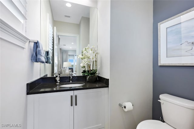 half bathroom featuring visible vents, recessed lighting, toilet, and vanity