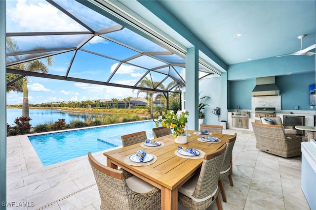 outdoor pool with grilling area, a water view, a lanai, a patio area, and an outdoor kitchen