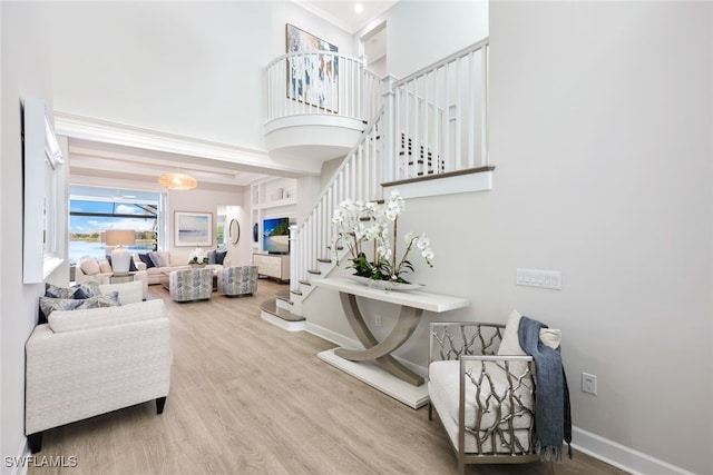 living area featuring stairway, wood finished floors, baseboards, and a towering ceiling