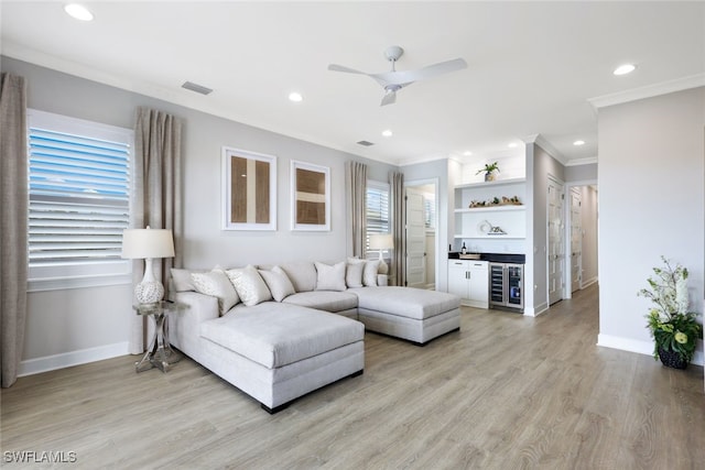 living area with light wood finished floors, visible vents, baseboards, a dry bar, and ornamental molding