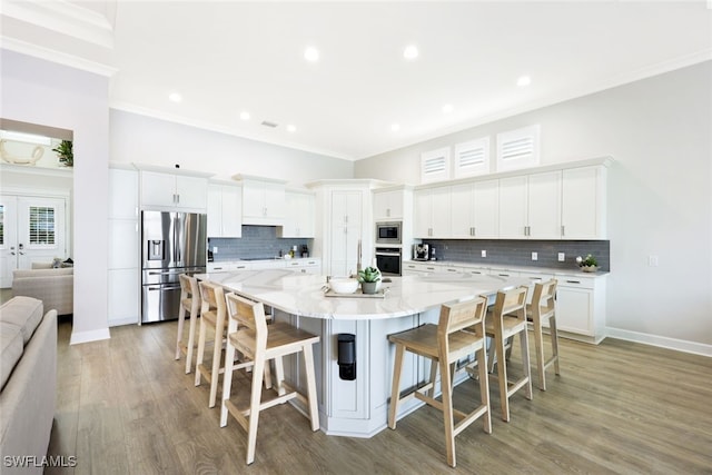 kitchen featuring a spacious island, ornamental molding, stainless steel appliances, french doors, and white cabinetry