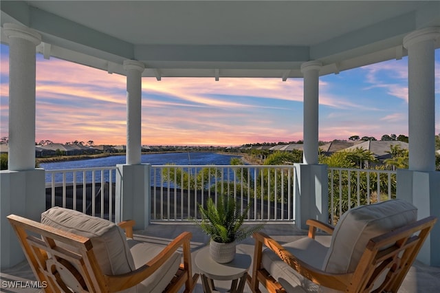 balcony at dusk featuring a water view