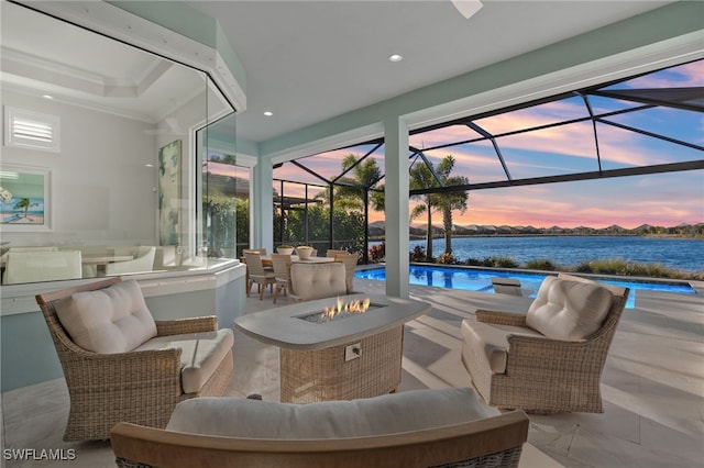 patio terrace at dusk featuring an outdoor living space with a fire pit, a lanai, an outdoor pool, and a water view