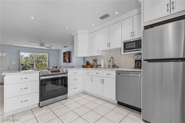 kitchen with kitchen peninsula, ceiling fan, tasteful backsplash, white cabinetry, and stainless steel appliances