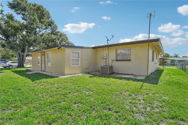 back of property with central AC and a yard