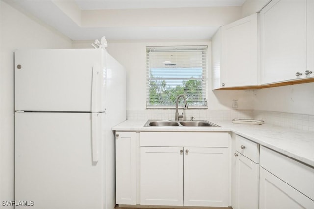 kitchen featuring white cabinets, sink, and white fridge