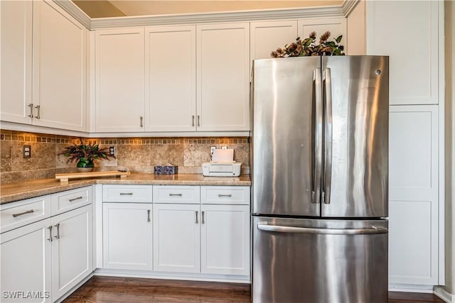 kitchen featuring white cabinetry, stainless steel refrigerator, tasteful backsplash, and light stone counters