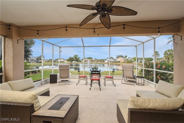 view of patio with a lanai, ceiling fan, a water view, and an outdoor living space with a fire pit