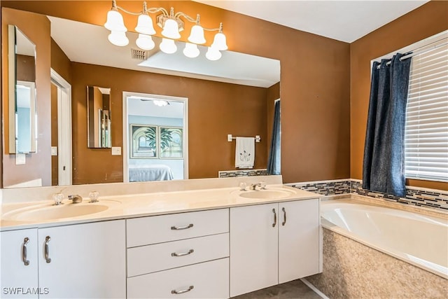 bathroom featuring tiled tub and vanity