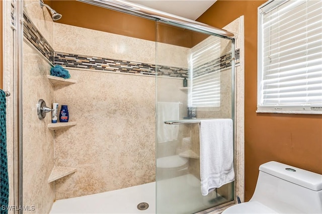 bathroom featuring a shower with shower door and toilet