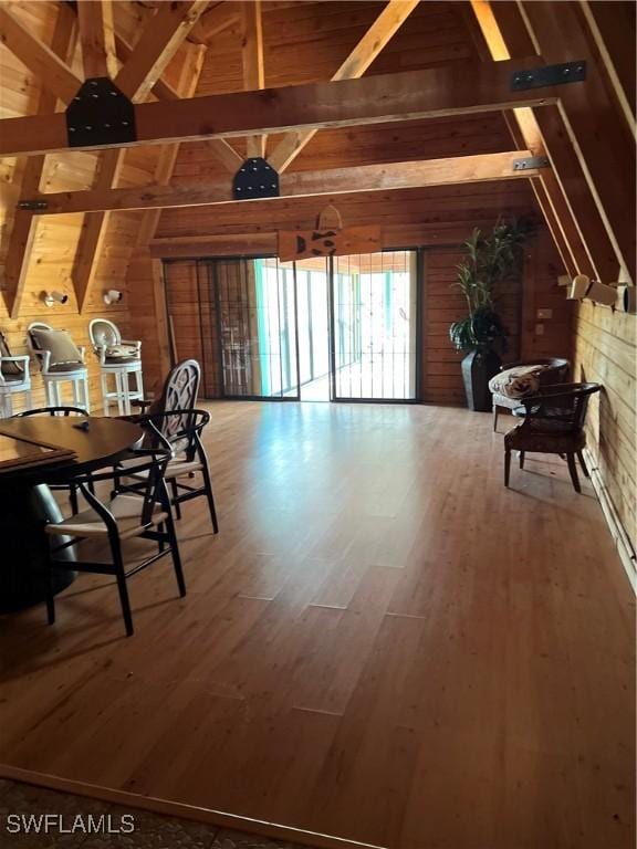 dining area with vaulted ceiling with beams, hardwood / wood-style flooring, and wood walls