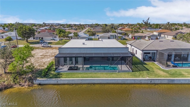 rear view of house featuring a yard, a water view, and glass enclosure