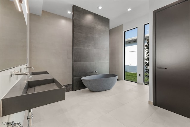 bathroom with a tub to relax in, sink, and tile walls