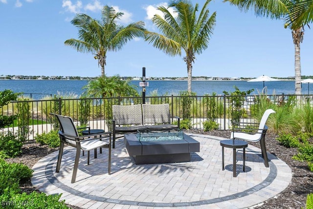 view of patio with a water view and an outdoor living space with a fire pit