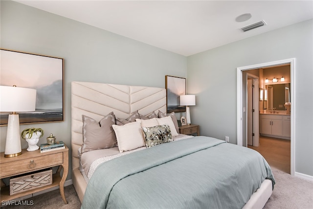 bedroom with ensuite bathroom, light colored carpet, and sink