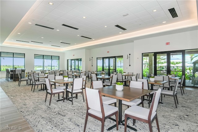 dining room featuring a raised ceiling, french doors, and a healthy amount of sunlight