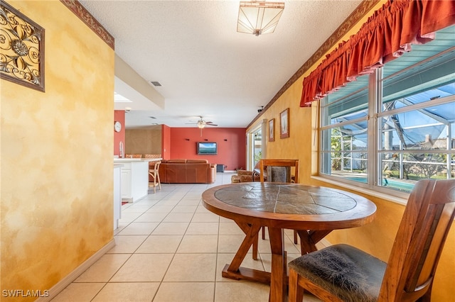 tiled dining space with ceiling fan and a textured ceiling