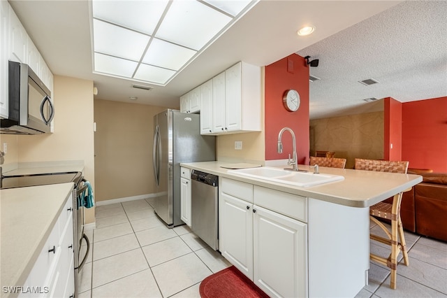 kitchen with white cabinetry, sink, kitchen peninsula, a breakfast bar area, and appliances with stainless steel finishes