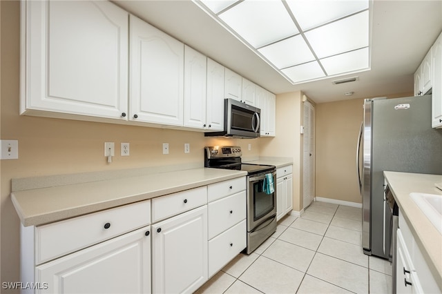 kitchen with white cabinets, stainless steel appliances, and light tile patterned floors