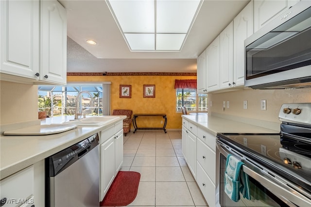 kitchen featuring sink, white cabinets, stainless steel appliances, and light tile patterned floors