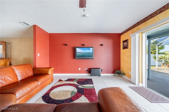 living room with ceiling fan, light tile patterned floors, and a textured ceiling