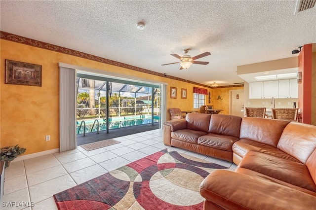 tiled living room featuring ceiling fan, sink, and a textured ceiling