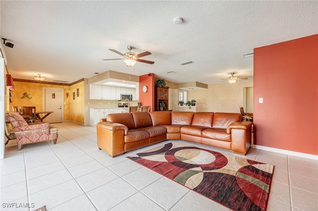 tiled living room with a textured ceiling and ceiling fan