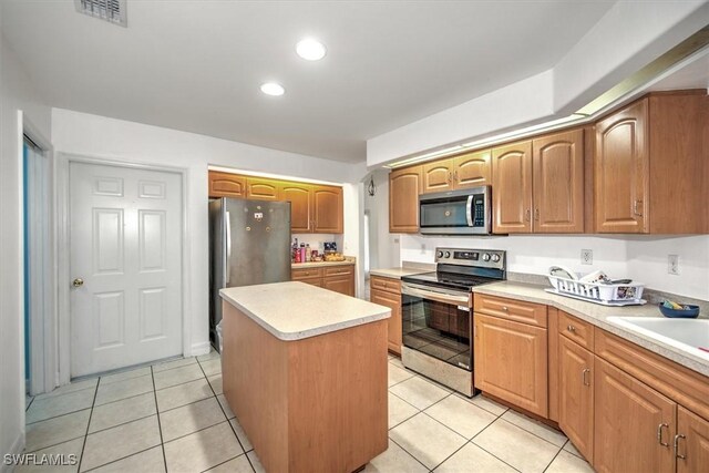 kitchen featuring a kitchen island, light tile patterned flooring, sink, and appliances with stainless steel finishes