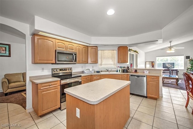 kitchen featuring kitchen peninsula, stainless steel appliances, sink, a center island, and light tile patterned flooring