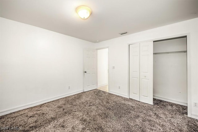 unfurnished bedroom featuring dark colored carpet and a closet