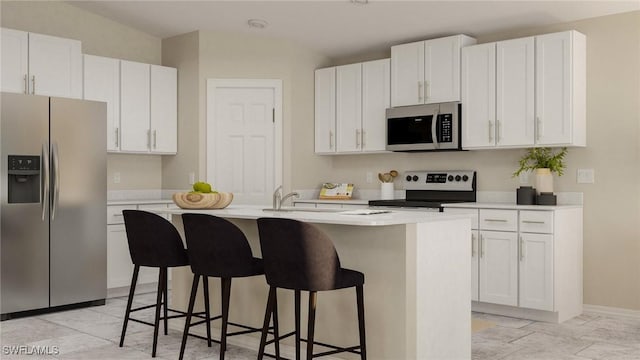 kitchen featuring a kitchen island with sink, sink, a breakfast bar area, white cabinetry, and stainless steel appliances